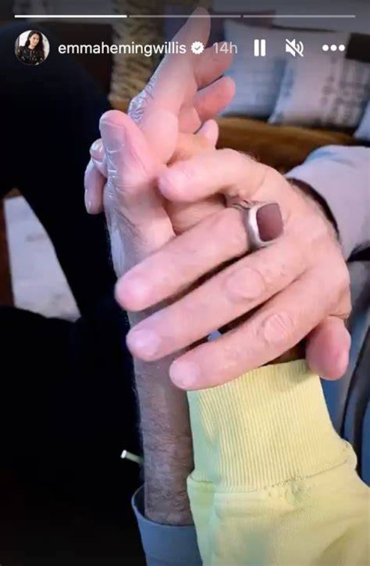 Bruce and Emma holding hands and smiling on a red carpet