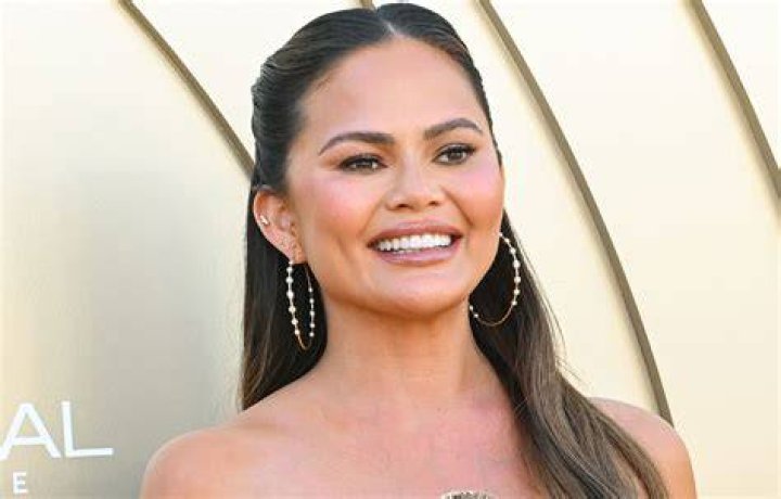 Chrissy smiling in white crop and skirt