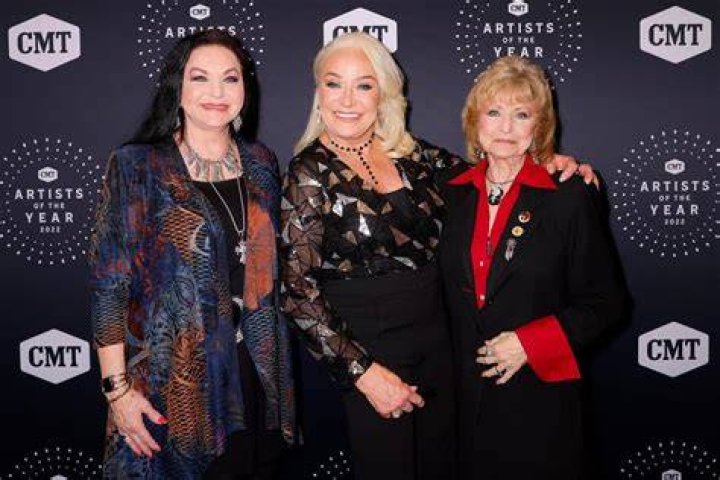 Country singers and sisters Loretta Lynn [Left] and Crystal Gayle flank Loretta's husband Mooney Lynn at a soiree in circa 1976. | Source: Getty Images