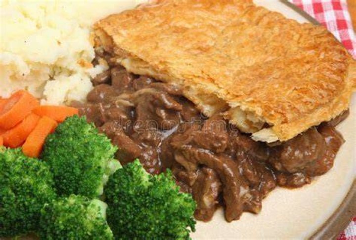 Pie, vegetables and mash on a plate next to a pint of ale
