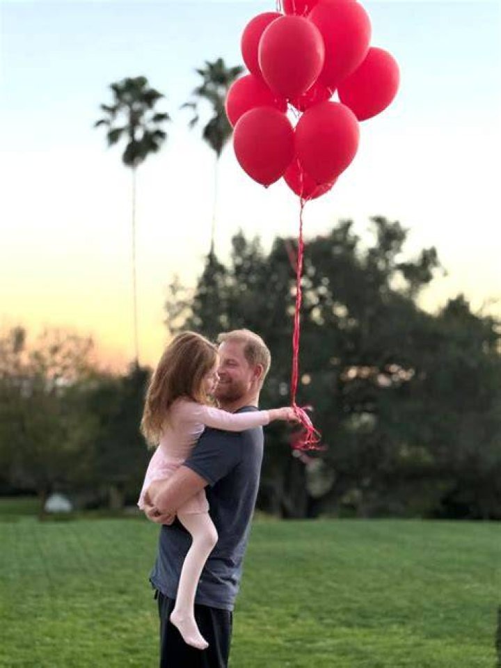 Prince Harry in red jacket and Meghan in red caped dress