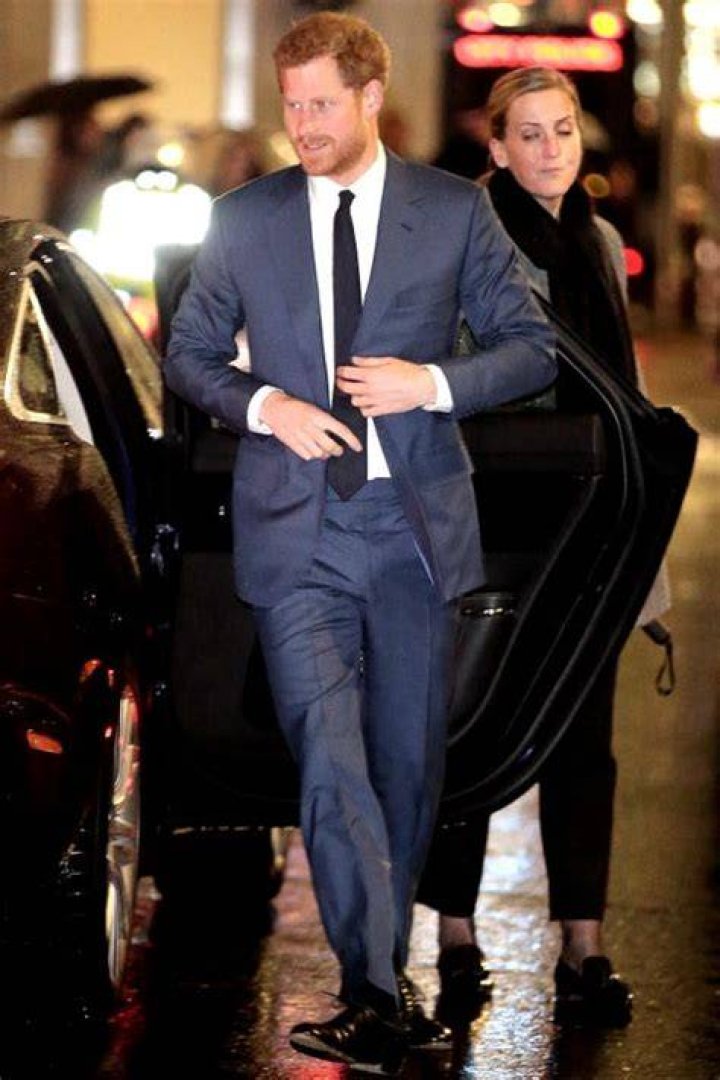Prince Harry in suit walking with Meghan in ivory caped dress