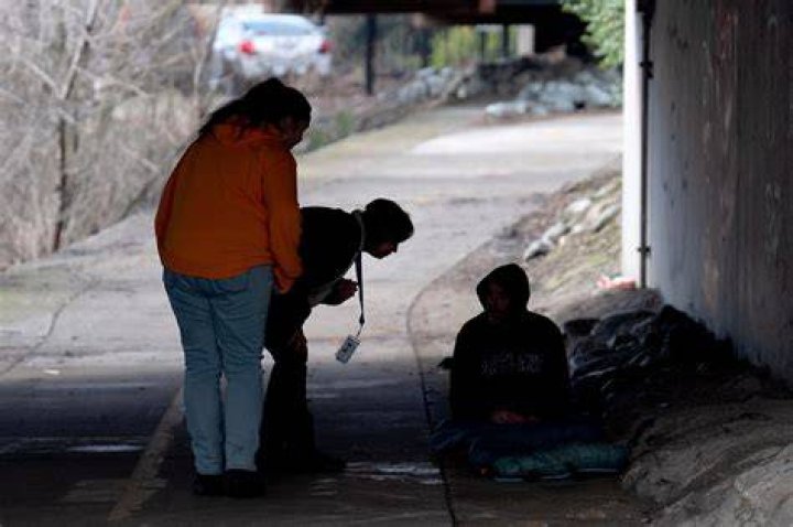 Resiliency Empowerment Support Team (REST) team member Beth Perkins, give a homeless person a hand warmer during a visit to a homeless camp in Chico, Calif., Feb. 8, 2024. A measure aimed at transforming how California spends money on mental health will go before voters in March as the state continues to grapple an unabated homelessness crisis. The REST Program does daily visits to homeless encampments to get them into treatment or housing. Butte County officials fear the REST program would lose its funding if California voters approve Proposition 1.(AP Photo/Rich Pedroncelli)