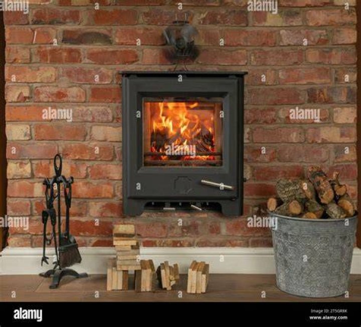 Roaring fire in log burner under large arched fireplace