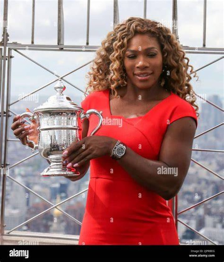 Serena Williams posing on the beach in a black one-piece swimsuit