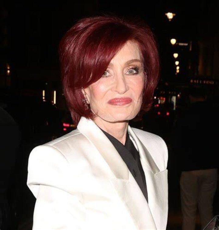 Sharon Osbourne in a white dress and gold necklace